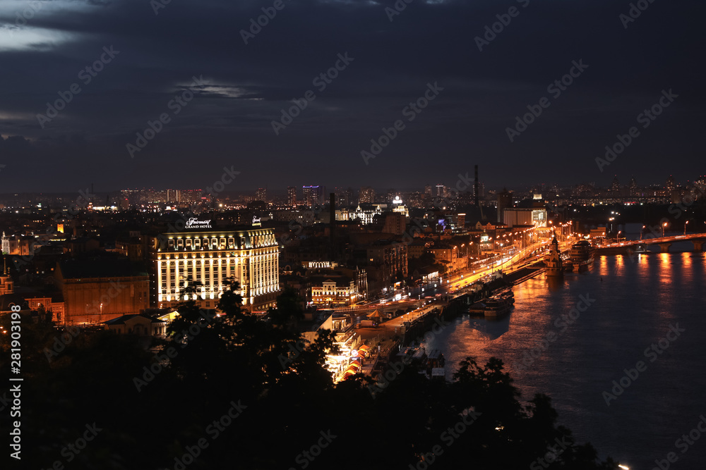 KYIV, UKRAINE - MAY 21, 2019: Beautiful view of night city with illuminated Fairmont Grand Hotel and other buildings near river