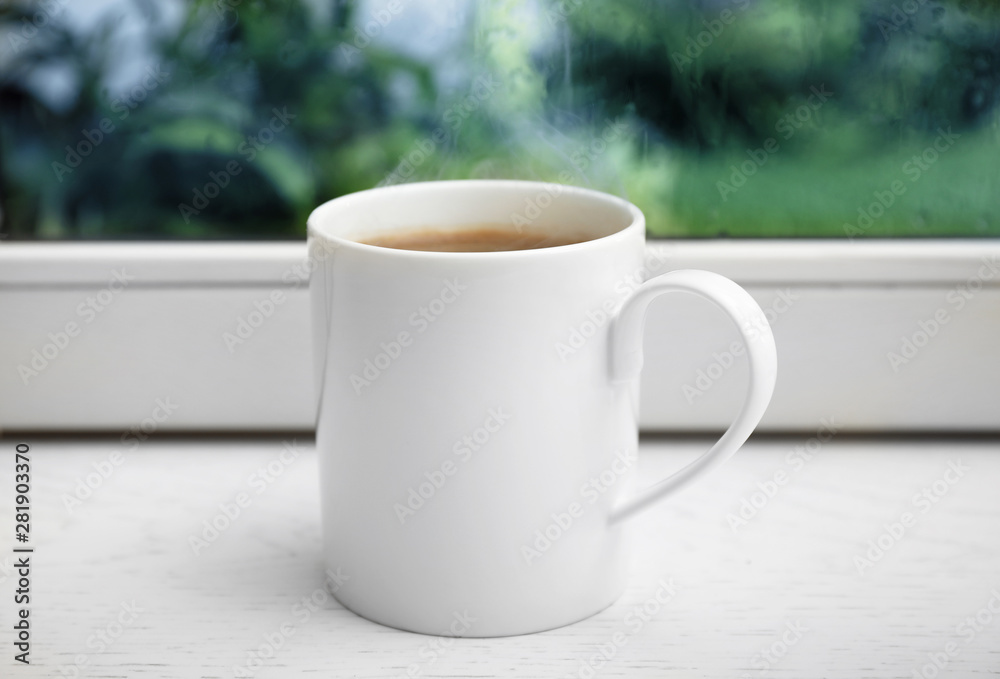 Cup of hot coffee on white wooden windowsill