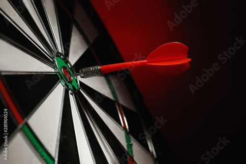 Color arrow hitting target on dart board against red background