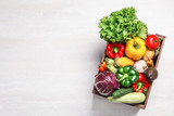 Crate with different fresh vegetables on light background, top view. Space for text