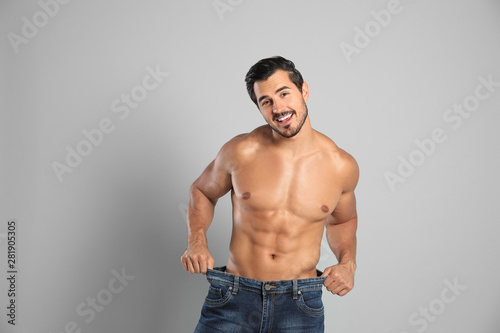 Young man with slim body in old big size jeans on grey background