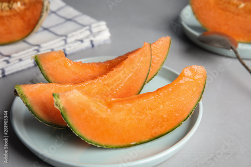 Slices of ripe cantaloupe melon in plate on grey table