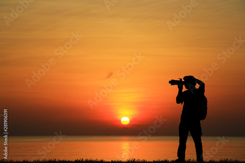 Silhouette of photographer with his camera on sunrise