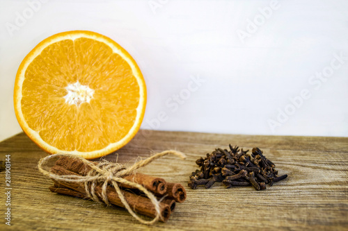Spices and sliced fresh orange on an old wooden cutting board. Ripe orange, Cinnamon sticks and cloves on wooden background, close up. Selective focus. Copy space.