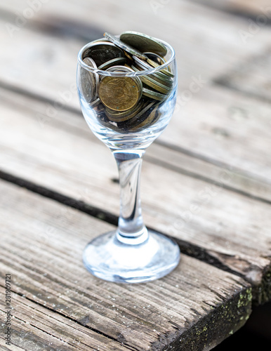 Coins in a glass cup on a wooden board