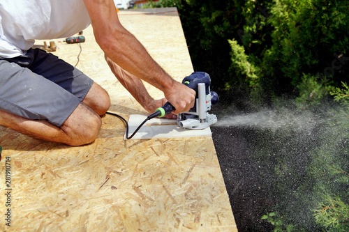 preparation with milling cutter for iron brackets of a roof gutter on construction site. male Hand of carpenter holds a carpentry tool. gutters water drainage system with milling woodworking machine. 