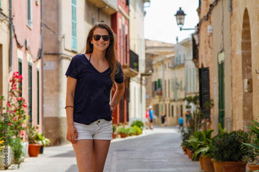 Junge schöne lachende Frau in einer Häuser-Gasse der Altstadt Alcudia Mallorca Spanien Shopping Sight Seeing 