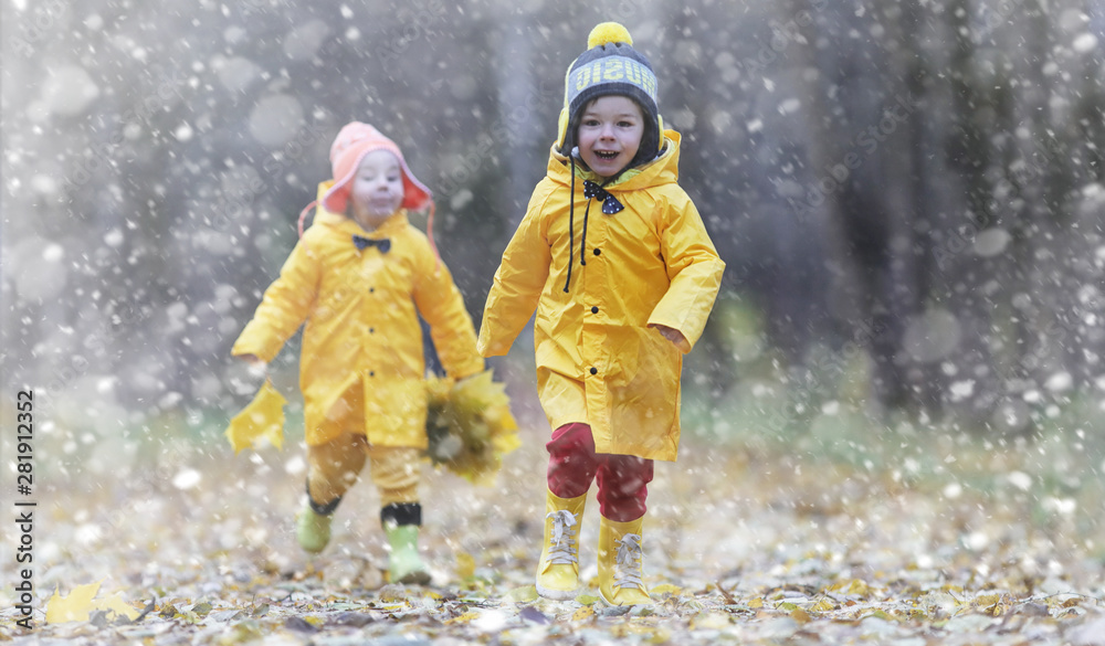Toddlers on a walk in the autumn park. First frost and the first snow in the autumn forest. Children play in the park with snow and leaves.