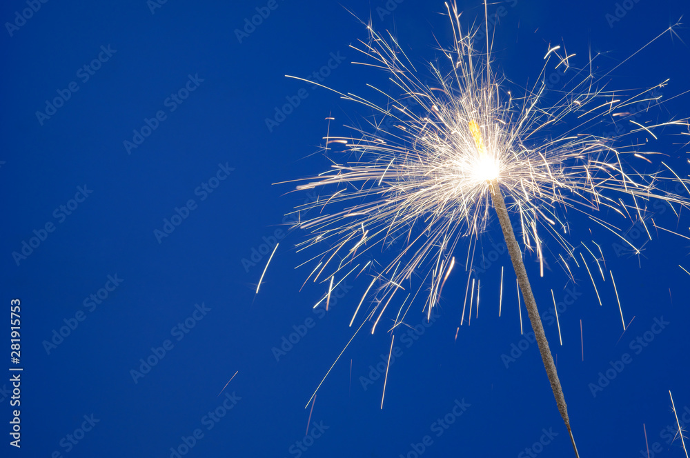 Burning christmas sparkler on blue background with copyspace