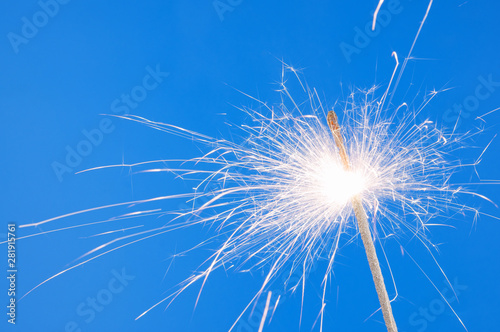 Burning christmas sparkler on blue background with room for text