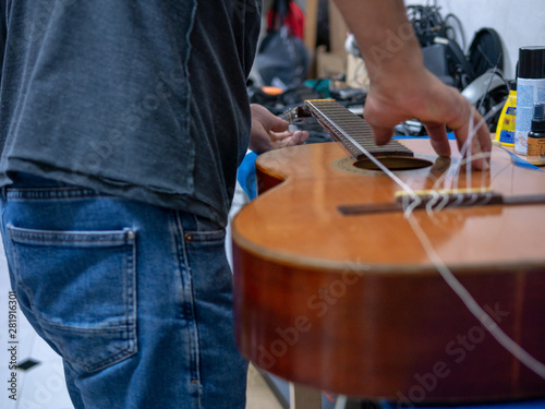 hands of a man repairing a spanish guitar