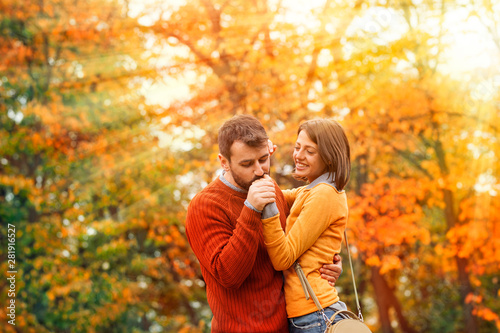 Young man kissing hand his adorable girl in sunny autumn park