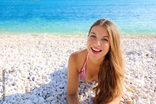 Happy beautiful smiling girl enjoying relax lying on the beach looking at camera. Summer holidays concept. Copy space.