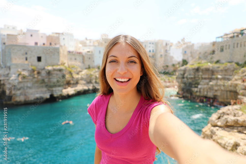 Smiling woman take selfie in her summer vacation in Polignano a mare, Mediterranean Sea, Italy