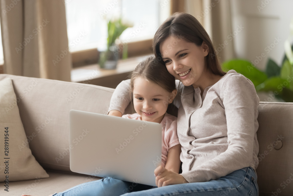 Mother with daughter sitting on couch watching movie on laptop Mother with daughter sitting on couch watching movie on laptop
