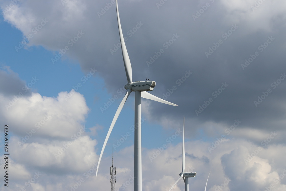 Modern windturbines with grey cumulus clouds on the sky Modern windturbines with grey cumulus clouds on the sky