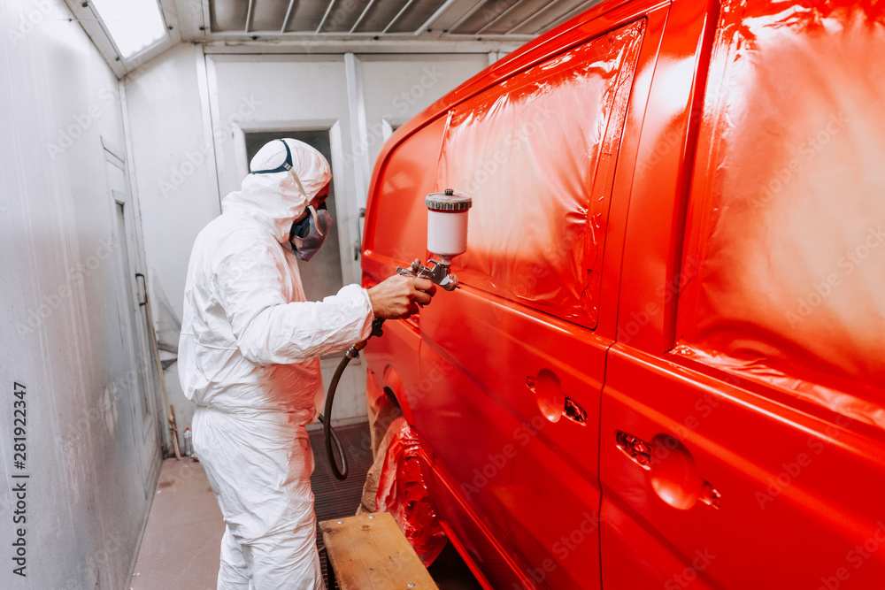 Auto mechanic working and painting a red van in a special booth Auto mechanic working and painting a red van in a special booth