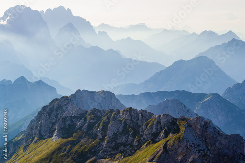 Layers of silhouettes of mountain ridges and peaks in the Italian Alps, at sunset. View from the route down from Mangart (Mangrt) peak, Julian Alps, Triglav, Slovenia. photo