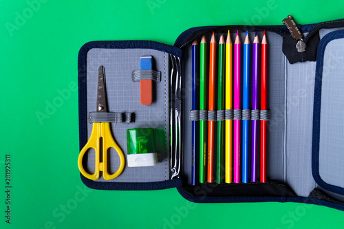 Fotografie, Obraz Pencil case with school supplies on a green paper background with copy space