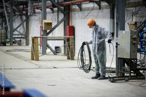 A builder in a work robe is engaged in the installation and construction of an industrial building at the Zvezda shipyard