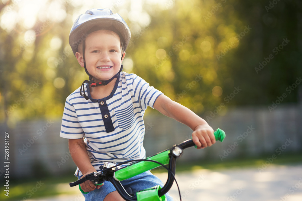 Obraz premium Happy 3 year old boy having fun riding a bike