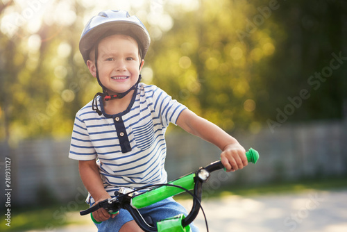 Happy 3 year old boy having fun riding a bike