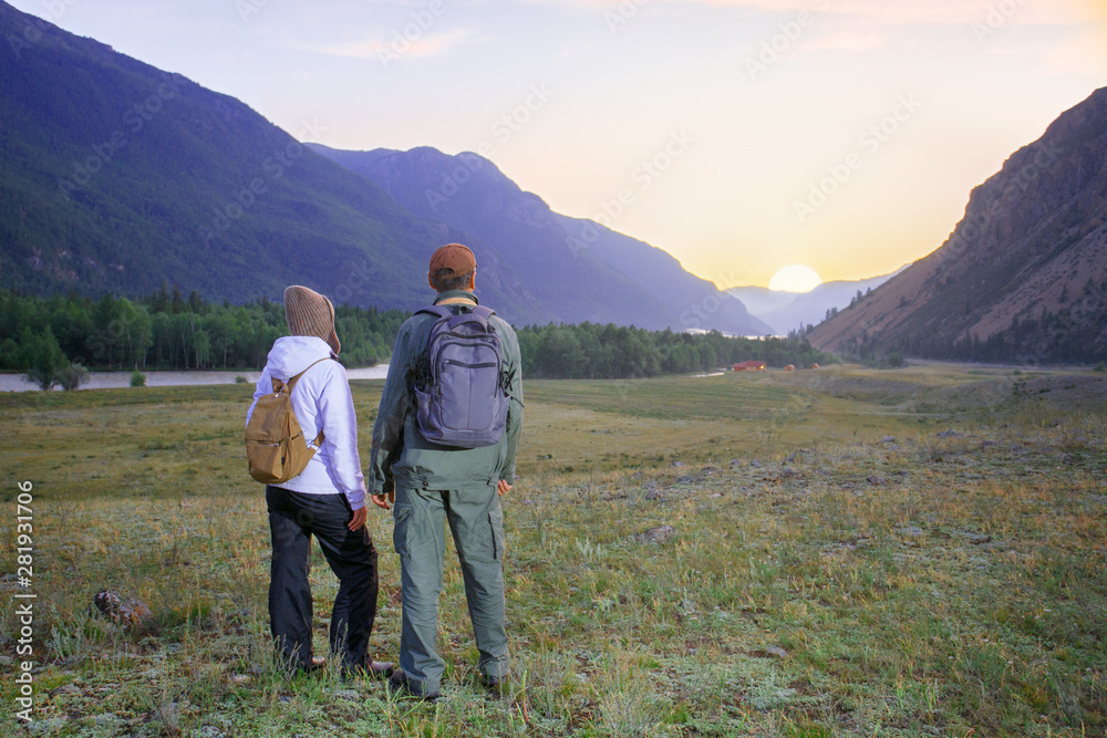 Hikers with backpacks relaxing. Happy couple feel freedom and enjoy the beautiful autumn forest in the mountains and looking together on sunset.