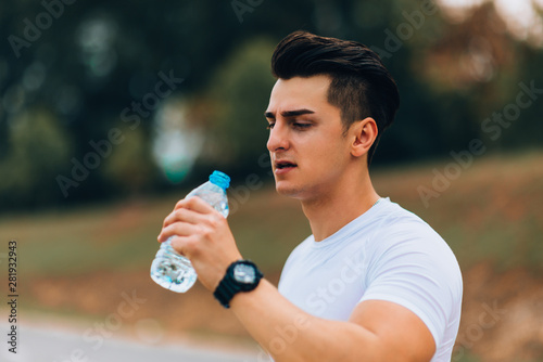 Sportman doing weightlifting drinking water soda