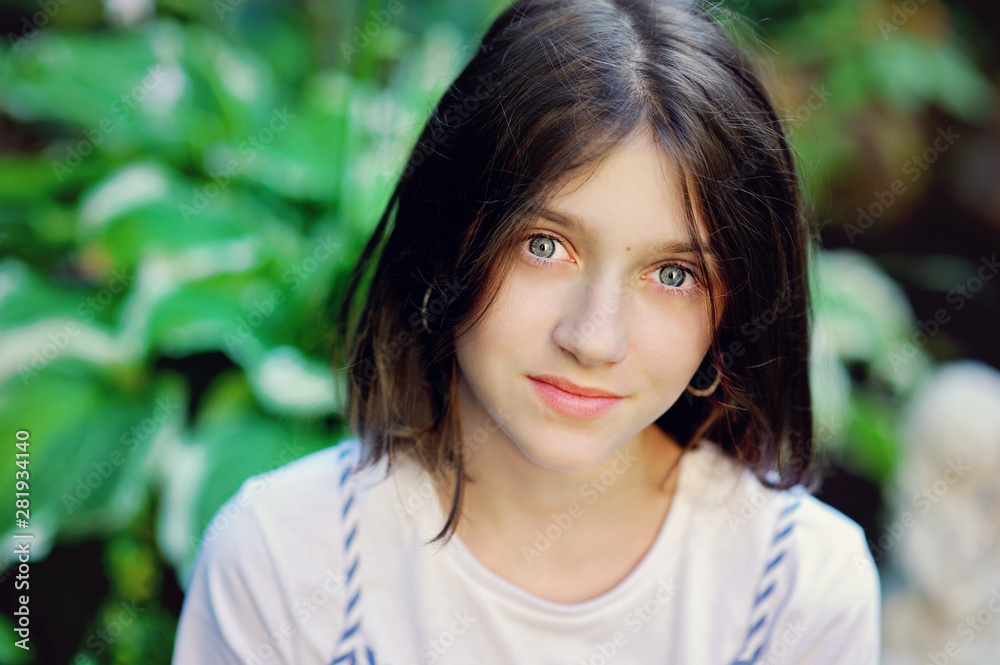 Beautiful smiling teenage girl in blue blouse, against green of summer park. Beautiful smiling teenage girl in blue blouse, against green of summer park.