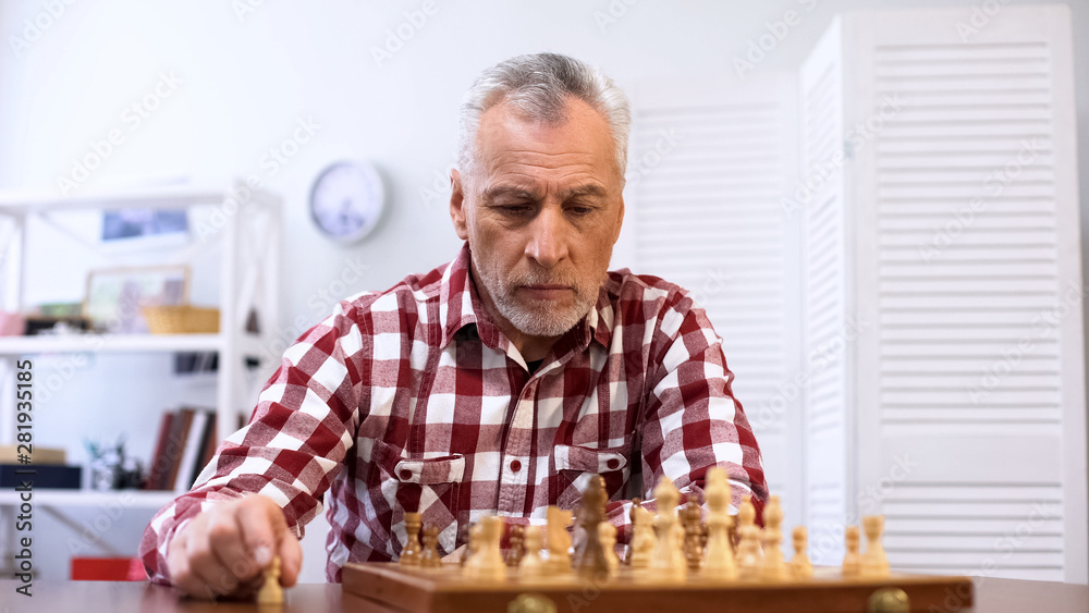 Concentrated old man playing chess alone, preparing for competition, strategy Concentrated old man playing chess alone, preparing for competition, strategy