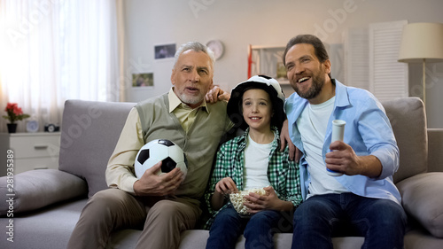 Granddad, dad and preteen son cheering for national football team at home, hobby