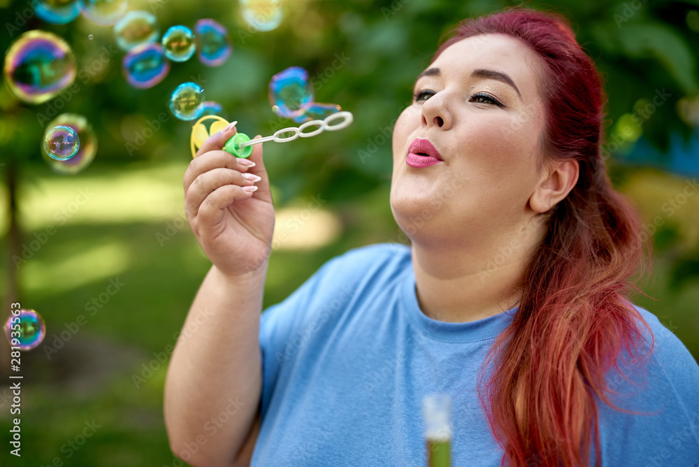 Young fat woman blowing bubble in the city