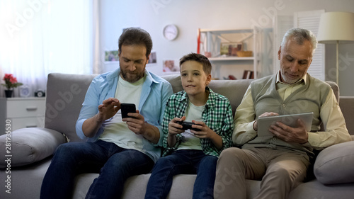 Adult males scrolling gadgets, preteen boy playing video game, gadget addiction