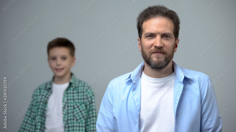 Middle-aged man smiling at camera little boy standing behind, childhood memories Middle-aged man smiling at camera little boy standing behind, childhood memories