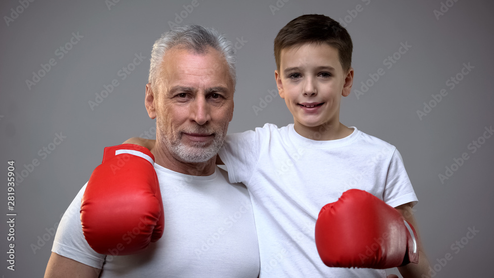 Active senior male and boy in boxing gloves looking to camera, healthy lifestyle Active senior male and boy in boxing gloves looking to camera, healthy lifestyle