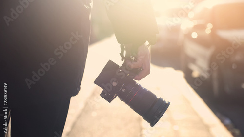 Φωτογραφία Professional photojournalist holding camera, walking on street, paparazzi spying