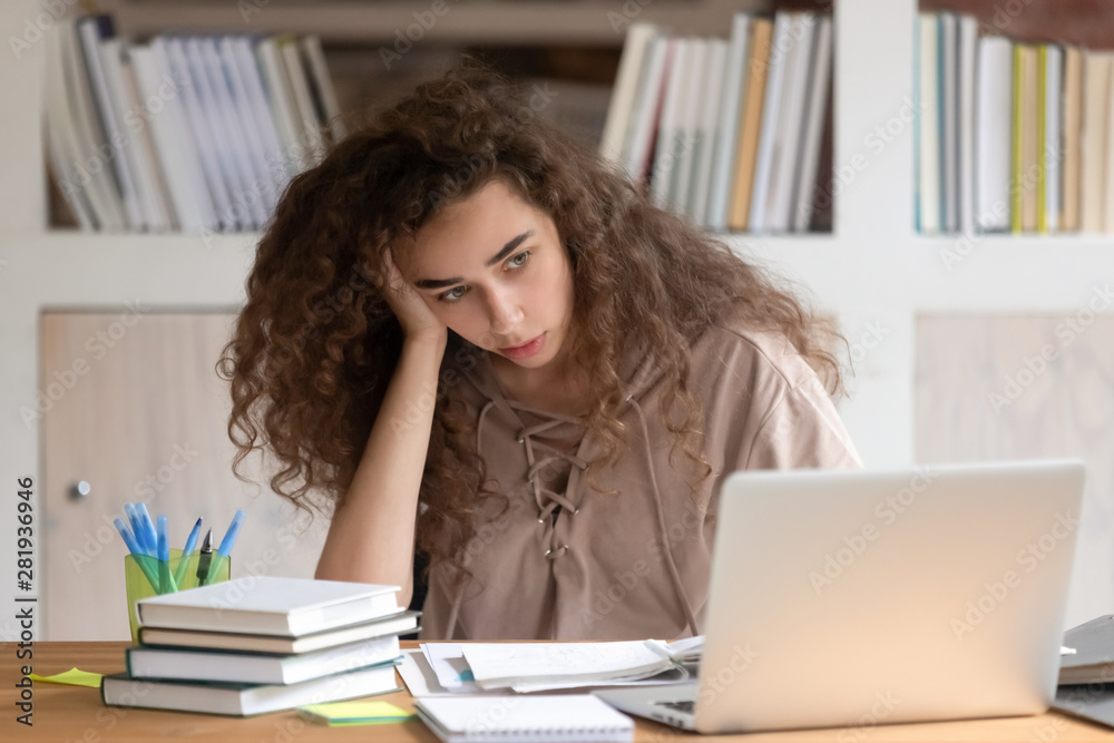 Loaded with homework tasks girl sitting at desk feels tired Loaded with homework tasks girl sitting at desk feels tired