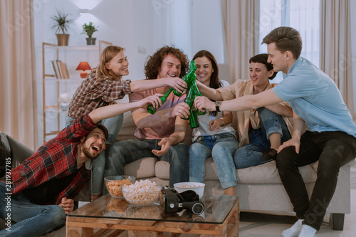 In a luminous house in living room a big company of friends multi ethnic guys watching a football match and celebrating the victory of their best team ladies photo