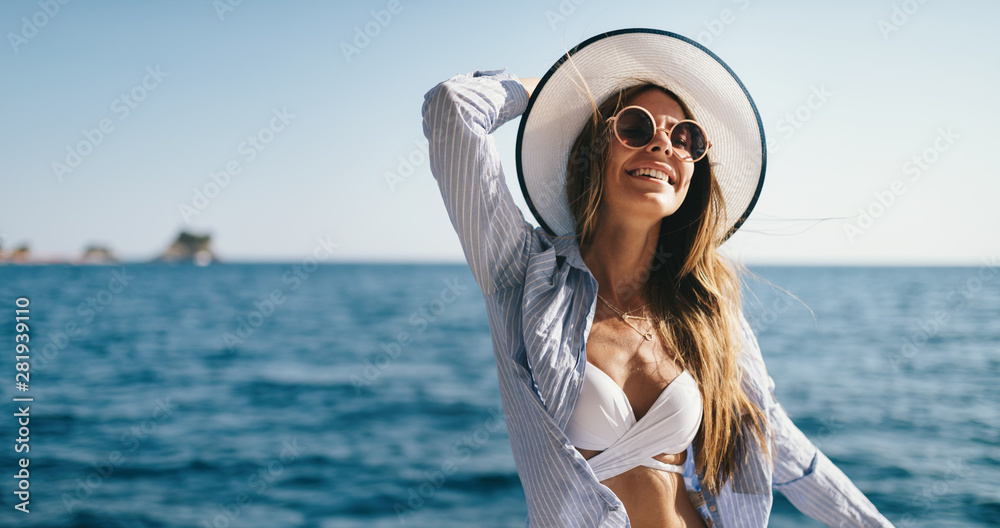 Beach vacation. Beautiful woman in sunhat and bikini enjoying summer trip