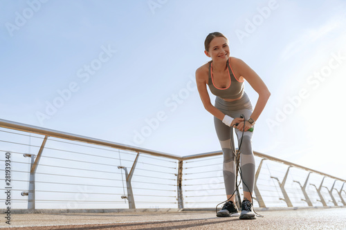 Happy sportive lady with jump rope on bridge