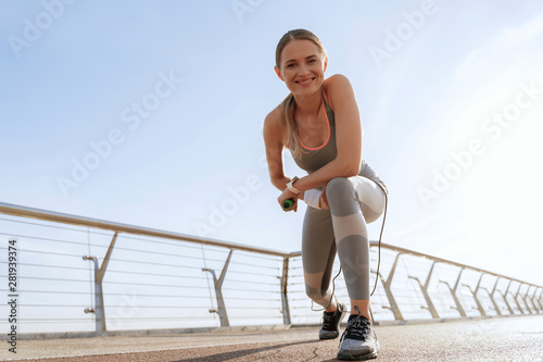 Happy athletic lady with jump rope on bridge