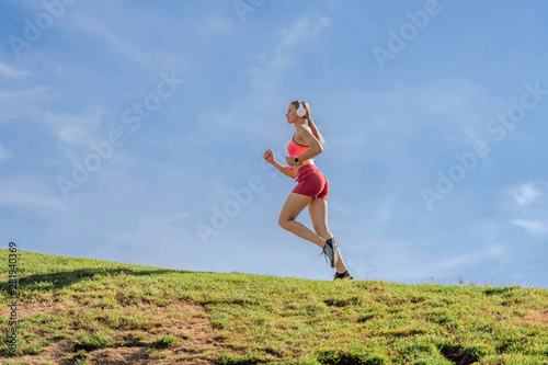 Young lady is running on green hill