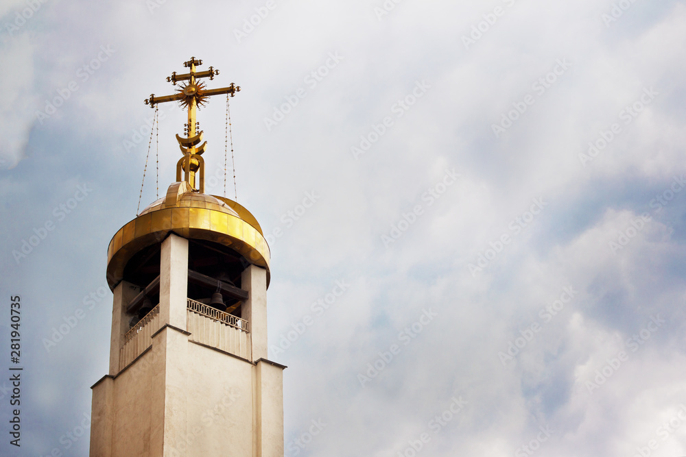 The bell tower of the Orthodox Church in clear weather with natural light on the background of the sky with white clouds
