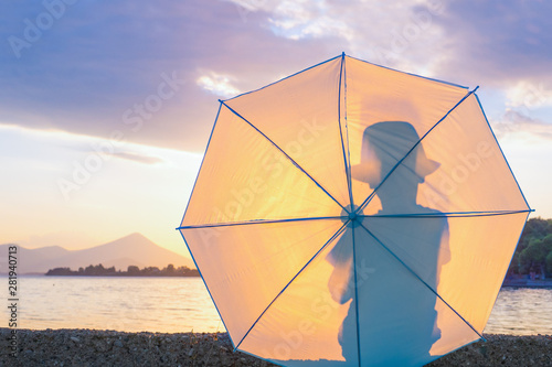 Stylish hipster. SILHOUETTE CLOSE UP: Kid in hat hides behind umbrella Silhouette of a man back view on sunset sunrise background, the effect of backlight, darkened picture. Copy space