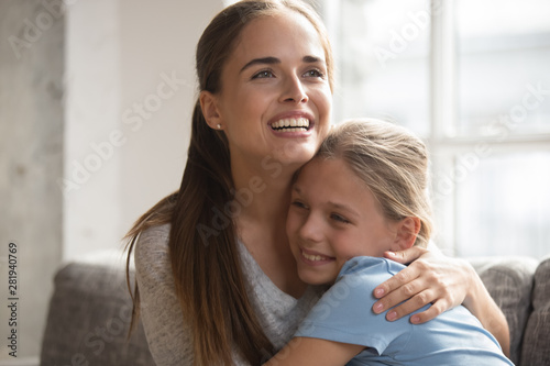Happy mother embracing little daughter family sit on couch