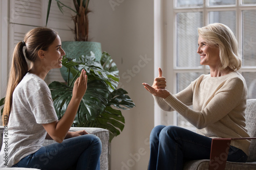 Grown up daughter talk with elderly mother using sign language photo