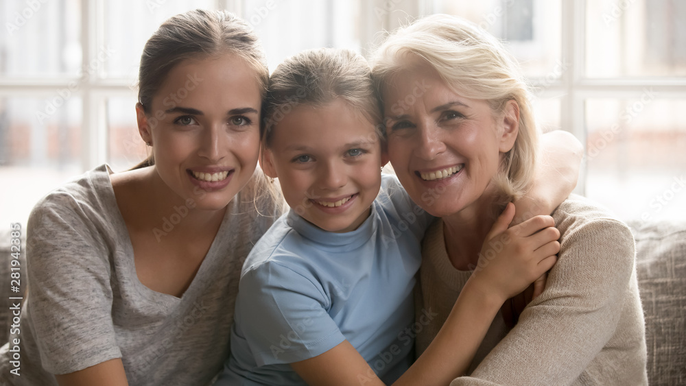 Three generations of women sitting on couch looking at camera Three generations of women sitting on couch looking at camera