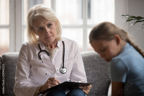 Scared closed child at appointment with general practitioner or psychologist photo