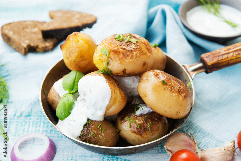 Fried potatoes in a pan with sour cream on rustic background Fried potatoes in a pan with sour cream on rustic background