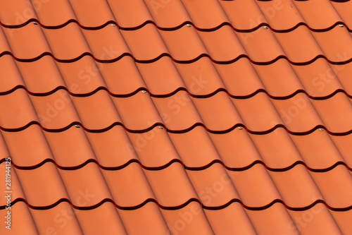 Overlapping rows of red tiles roof in Estonia, ridge tiling material regular pattern background in horizontal orientation.